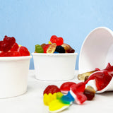 Colorful gummies in small white bowls on a light blue background