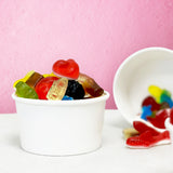 Colorful gummy candies in a white bowl against a pink background