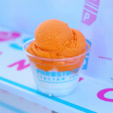 9 oz custom printed plastic cup with Phrostbite Italian Ice logo, filled with white and orange gelato, on white background