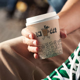 10 oz. Full Wrap Recyclable Paper Cup displaying "latte", held with arm resting on a thigh.