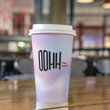 16 oz. Multicolor Recyclable Paper Cup displaying "ohh tea shop" on a wooden table.