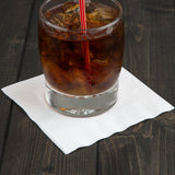 Blank 3-PLY White Beverage Napkin with a glass of coke resting on top, on a wooden table