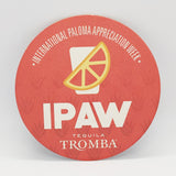 Round red coaster, with a print of "IPAW" and illustration of an orange slice, on white background