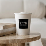 12 oz paper cup with black square "Icon" logo, filled with drink and marshmallow, on wooden table
