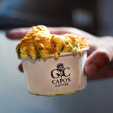 5 oz paper food container with black "Capo's Coffee" logo and a rose, filled with melting ice cream, held by a hand