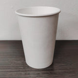 Blank white 8 oz paper cup on grey wooden table, white wall in background