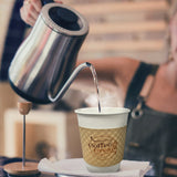 White paper coffee cup with a kraft brown sleeve featuring the “Coffee & Cream” logo and a barista pouring hot water from a gooseneck kettle.