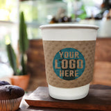 Custom Printed Kraft Brown White, paper cup with Kraft Brown Coffee Sleeve displaying "your logo here", resting on a wood coaster, served with two cupcakes on a wooden table in a cafeCoffee Sleeve