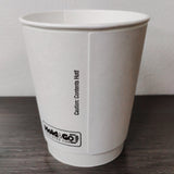 Blank white 12 oz premium double walled paper cup showing seam, on grey wooden table, white wall in background