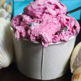 16 oz paper food container, filled with berry ice cream, on a black table