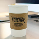White, paper cup with Kraft Brown Coffee Sleeve displaying "Spectacular Science" logo, on a brown office desk